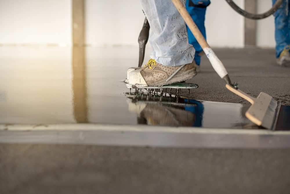 Worker working on the floor of an industrial building with special shoes to avoid damaging the