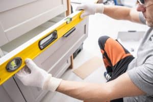 Professional Cabinetmaker Fitting Kitchen Furniture Drawer and Checking Levels