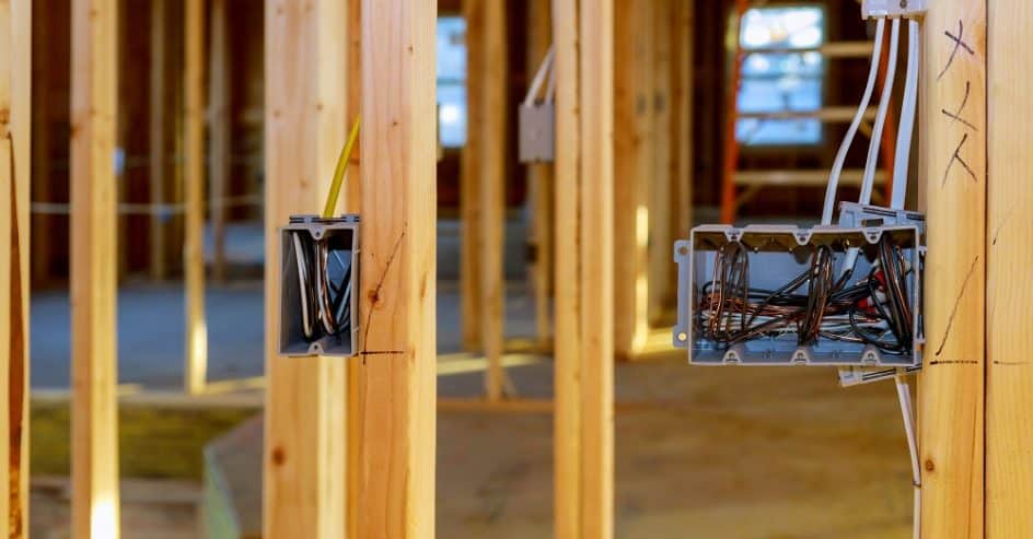 Electrical socket boxes with wires of wooden beams in a wall under construction unfinished frame