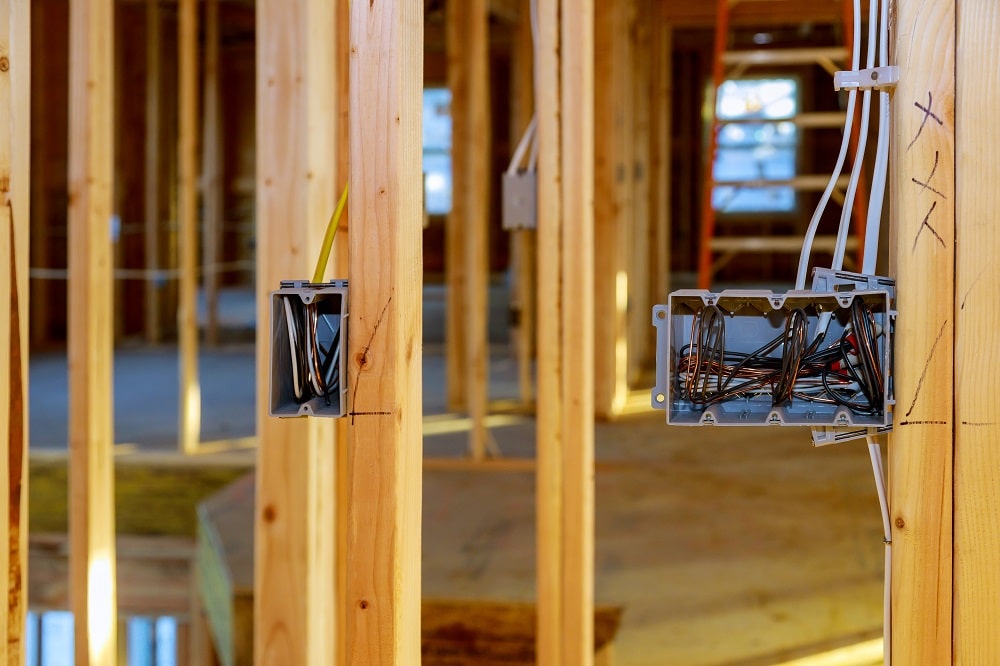Electrical socket boxes with wires of wooden beams in a wall under construction unfinished frame