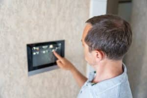 Man using tablet panel application for control smart home living. Wireless device controller for home automation IoT on the wall. High quality photo