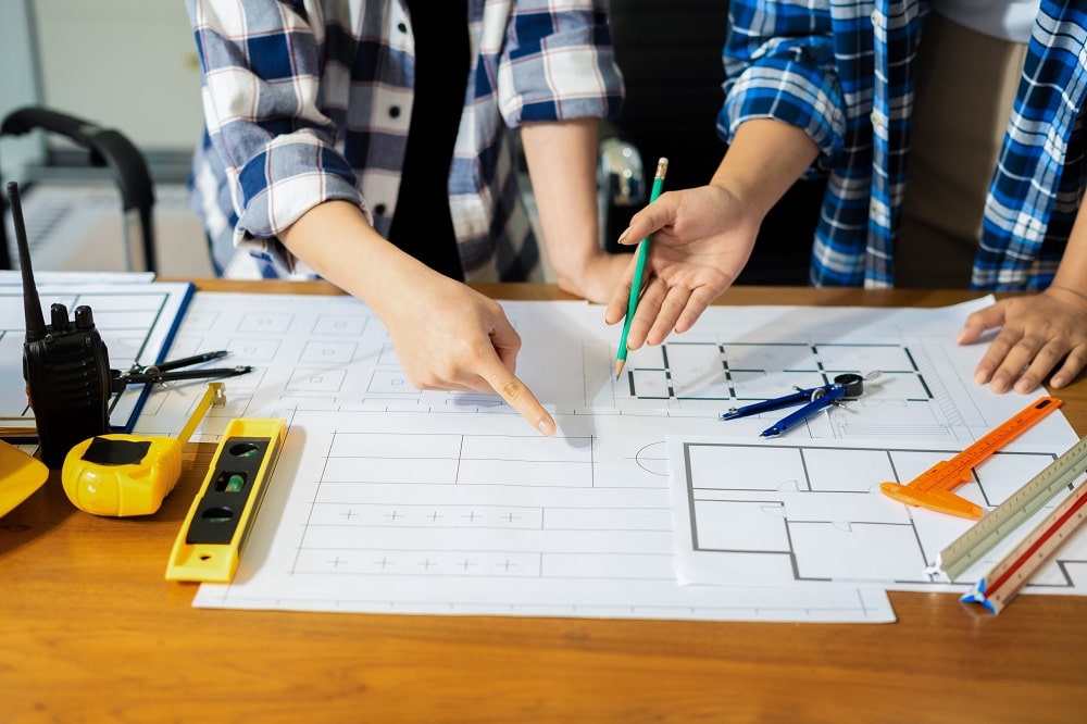 Person's engineer Hand Drawing Plan On Blue Print with architect equipment, Architects discussing at the table, team work and work flow construction concept.